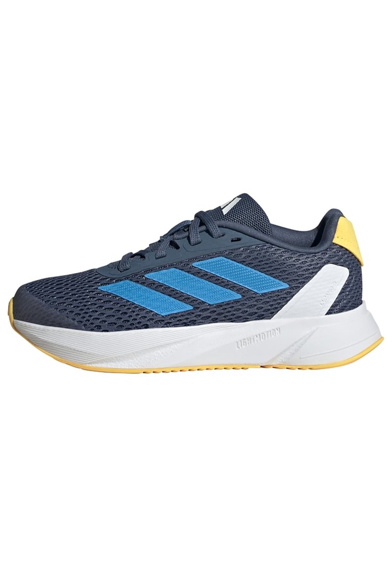 Zapatilla deportiva en color navy con parte superior de malla, rayas azules, una media suela blanca y detalles amarillos en el talón. Cuenta con una suela de goma para mayor tracción.