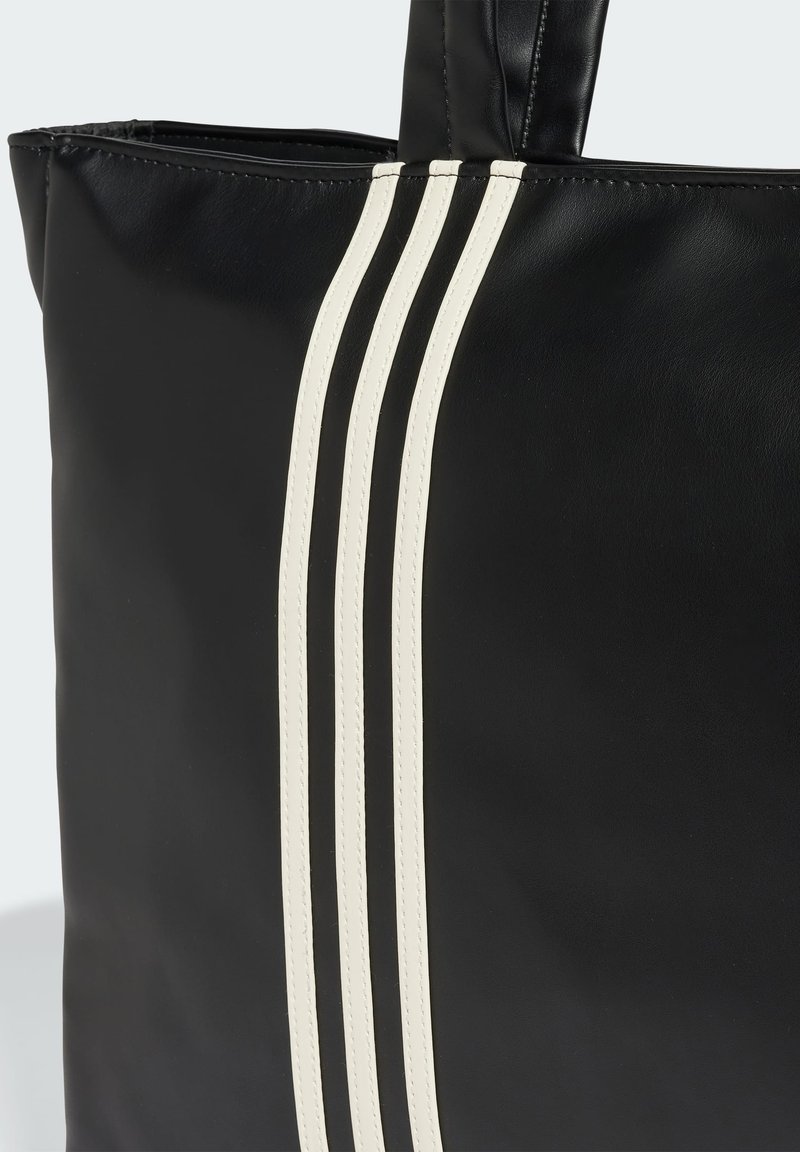 Schwarze Leder-Tote mit drei weißen parallelen Streifen an einer Seite, glatte Oberfläche und robuste Griffe zum Tragen.