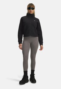 Black fleece jacket with high collar, gray textured leggings, and black ankle boots. Accessories include dark sunglasses. Simple, sporty design.