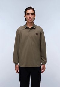 Langarm-Poloshirt in Olivgrün mit einer dreiknöpfigen Knopfleiste und einem runden Logoaufnäher auf der Brust. Weiches, glattes Gewebe mit entspannter Passform.