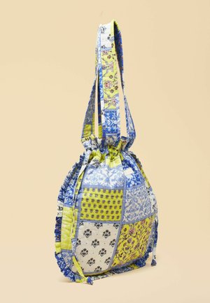 Kangaskassi, jossa nyörikiinnitys ja kirjailtua kuosia sinisissä, keltaisissa ja valkoisissa kukkakuvioissa sekä pitkät hihnat.