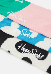 Kolorowe skarpetki w zielonym, różowym i czarnym kolorze z odważnymi wzorami: niebieskie i białe chmury oraz czarne kropki. Wszystkie mają logo "Happy Socks".