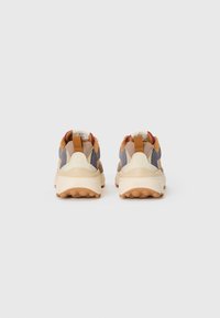 Multicolored sneakers featuring grey, beige, and brown materials with a chunky cream sole and pull tabs at the heel for easy wear.