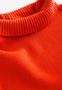 Sweter dzianinowy w intensywnym pomarańczowym kolorze z prążkowanym golfem. Posiada gładką teksturę i drobne szwy w całej konstrukcji.