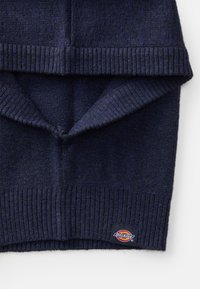 Temno modri pleteni pulover z rebrastimi manšeti in dnom, izdelan iz mehke tkanine. Vsebuje majhno Dickies oznako na spodnjem robu.