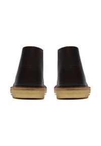 Bottes chelsea en cuir marron avec une texture lisse, un haut arrondi et une semelle en caoutchouc. Présentent des coutures contrastées et un talon bas.