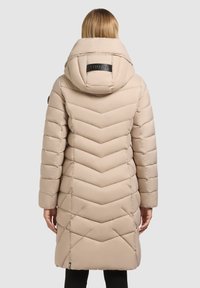 Bež prešita jakna z vzorcem ribje kosti, z veliko kapuco in označeno zadnjo stranjo. Gladek tekstura z dolgimi rokavi in srednjo dolžino.