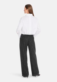 White button-up shirt with a back vent, paired with black pinstriped wide-leg trousers. The outfit features a clean, tailored design.