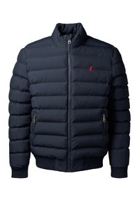 Chaqueta acolchada tipo puffer de color azul marino con cremallera frontal, bolsillos laterales con cremallera, puños acanalados y un pequeño logo bordado en rojo en el pecho.