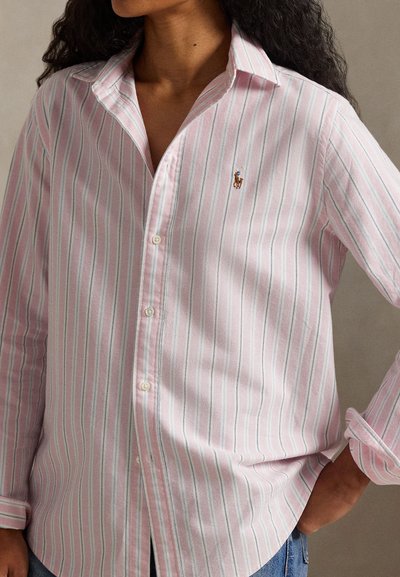 Πουκάμισο με ροζ και λευκές ρίγες, κουμπωτό, μακριά μανίκια, γιακάς στο λαιμό και κεντητό λογότυπο στο στήθος. Απαλή υφή υφάσματος.