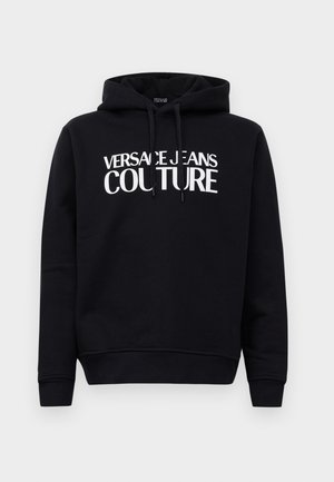 Crna dukserica s kapuljačom i bijelim natpisom "Versace Jeans Couture" sprijeda, s podesivim ušicom za kapuljaču, na jednostavnoj pozadini.