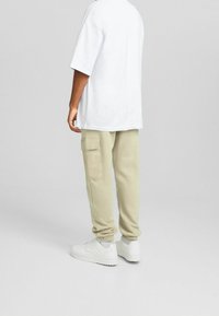 Vit oversized t-shirt, ljus beige cargobyxor med sidofickor och vita sneakers. Avslappnad passform med elastiska mudd på byxorna.