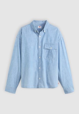 Chemise bleu clair à manches longues en tissu chambray. Elle présente un col, des manches longues, et une poche poitrine avec rabat et bouton.
