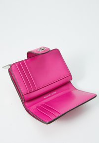 Pink læderpunge med flere kortlommer, sølvhardware og knaplukning. Indersiden har en glat tekstur og synligt mærkelogo.