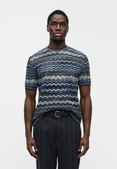 Cămașă tricotată cu mâneci scurte, cu un model zigzag multicolor în nuanțe de albastru, verde și bej. Guler rotund, siluetă ajustată.