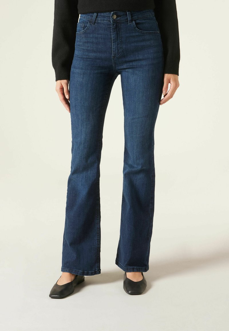Jeans acampanados de color azul oscuro con cintura alta, fabricados en tela de denim. Cuentan con cinco bolsillos y un cierre de botón. Textura suave.