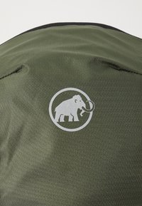 Tessuto verde testurizzato con un logo bianco circolare di un mammut con la proboscide sollevata, centrato sul prodotto.