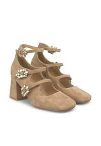 Scarpe beige in suede con tacco a blocco e punte squadrate, dotate di tre cinturini regolabili alla caviglia e dettagli decorativi in gioiello su ciascun cinturino.