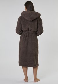 Brun, huva klädd kappr fylld av strukturerad fleece; den har ett knytbälte och långa ärmar, når ner till mitten av vaden.