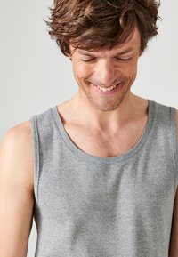 Canotta in cotone grigia con scollatura rotonda e ampie aperture per le braccia. Il tessuto ha una texture liscia, adatta per l'abbigliamento casual.