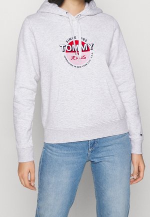 Felpa grigia chiara con tasca frontale, cappuccio con cordino e logo grafico in rosso e nero. Tessuto morbido, polsini e orlo a coste.
