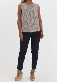Top senza maniche floreale con dettaglio arricciato, abbinato a pantaloni navy aderenti e zeppe in espadrille neutre con lacci alla caviglia.