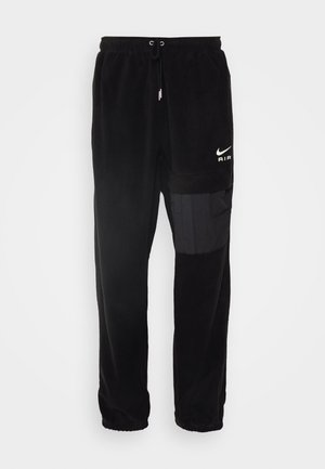 Zwarte joggingbroek van zacht fleece-materiaal. Voorzien van een elastische tailleband, een trekkoord en een zijvak met contrasterende stof.