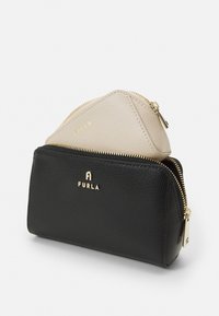 Svart lærpung med gullglidelåser og hardware, med en mindre beige trekantet pung plassert inni. Teksturert overflate med logo.