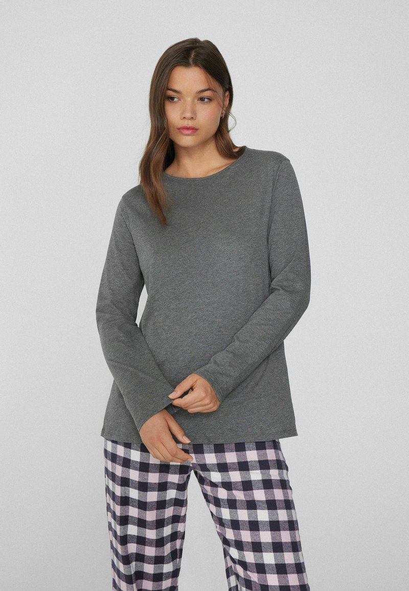 Šedý dlouhý rukáv top z jemného materiálu s kulatým výstřihem, v kombinaci s fialovými a bílými kostkovanými pyžamovými kalhotami. Jednoduchý a uvolněný střih.