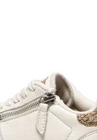 Baskets blanches en cuir avec un accent beige texturé, dotées d'une fermeture éclair argentée et de lacets blancs. Surface lisse et intérieur rembourré.