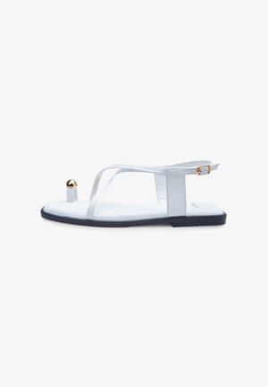 White flat sandals with a minimalist design, featuring thin straps, a gold accent on the toe, and a contrasting black sole.