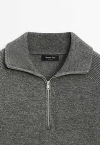 Grijze gebreide trui met een ritskraag, voorzien van een ribbelstructuur op de kraag en schouders. Etiket zegt "Massimo Dutti."