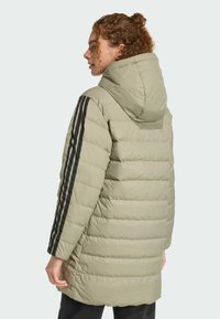 Pufová bunda vo svetlom olivovom odtieni s kapucňou, s čiernymi bočnými pruhmi, horizontálnou prešívanou textúrou a strednou dĺžkou.