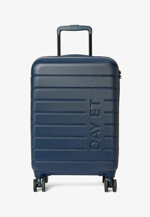 Valise rigide bleu foncé avec lignes texturées et logo embossé. Équipée d'une poignée rétractable et de quatre roues pour une maniabilité aisée.