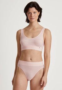 Brassière rose clair et slip taille haute assorti, fabriqués en tissu doux et extensible. Présentent une surface lisse et des coutures minimalistes.