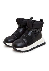Bottines noires à la cheville avec un col rembourré, dessus en cuir, bandes élastiques et semelle blanche dotée d'une semelle extérieure en caoutchouc texturé.