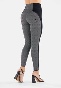 Leggings alta vita in pattern a scacchi nero e grigio con pannelli laterali, texture liscia e un dettaglio di cucitura curvata sul retro.