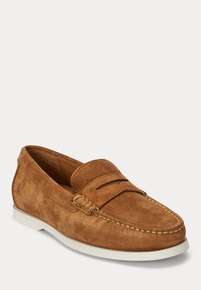 Καφέ σουέντ παπούτσι penny loafer με λευκή καουτσούκ σόλα και λεπτομερείς ραφές γύρω από τη μύτη και τις πλευρές.