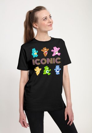 Sort T-shirt med farverige tegneserie-bjørne med forskellige symboler, tekst "ICONIC" i livlige bogstaver, korte ærmer og afslappet pasform.
