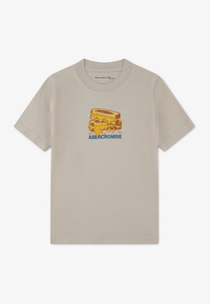 T-shirt beige à manches courtes avec un motif d'un sandwich au fromage grillé et le mot « ABERCROMBIE » sous l'image sur le devant.