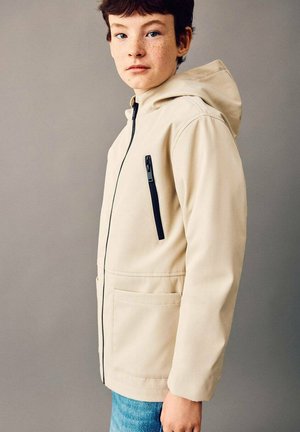 Veste imperméable beige avec capuche, dotée d'une poche poitrine zippée noire, de poches avant et d'une finition lisse. Tissu léger.