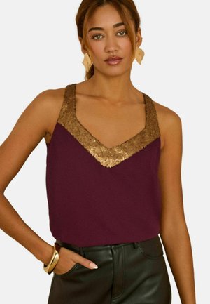 Burgundy sleeveless top with a V-neck, adorned with a gold sequin trim along the neckline, paired with black leather pants.