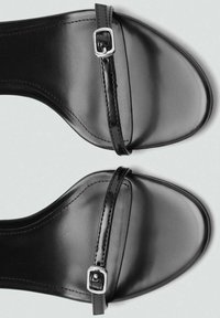 Zwarte leren sandalen met een glanzende afwerking, voorzien van een dunne band en een vierkante zilveren gespsluiting. Glad oppervlak en ergonomische vorm.