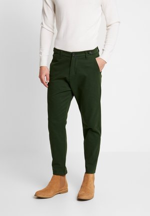 Chinos verde scuro con una vestibilità dritta, dotati di due tasche anteriori, chiusura con bottone e stivali Chelsea in camoscio marrone.
