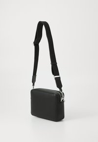 Black rectangular crossbody bag made of smooth synthetic material, featuring a zip closure and adjustable strap with logo detailing.