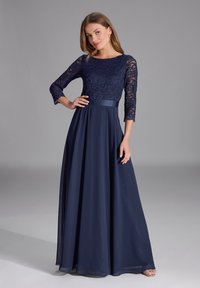 Abito da sera blu navy con corpino in pizzo e maniche a tre quarti, nastro in satin in vita e gonna fluida lunga fino al pavimento.