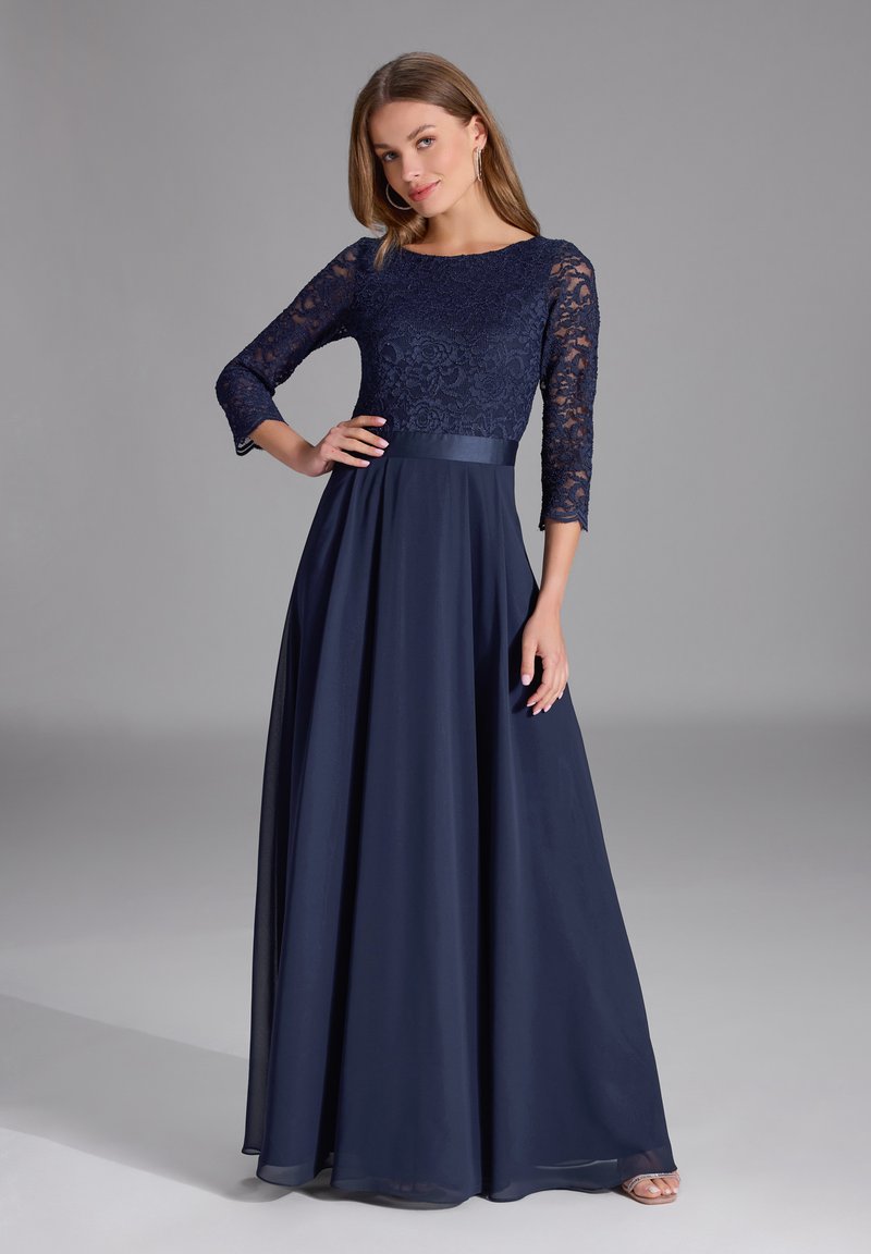 Abito da sera blu navy con corpino in pizzo e maniche a tre quarti, nastro in satin in vita e gonna fluida lunga fino al pavimento.