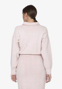 Hellrosa gestrickter Pullover mit Kragen, langen Ärmeln und strukturiertem Tupfenmuster. Der Pullover verfügt über gerippte Bündchen und einen gerippten Bund.