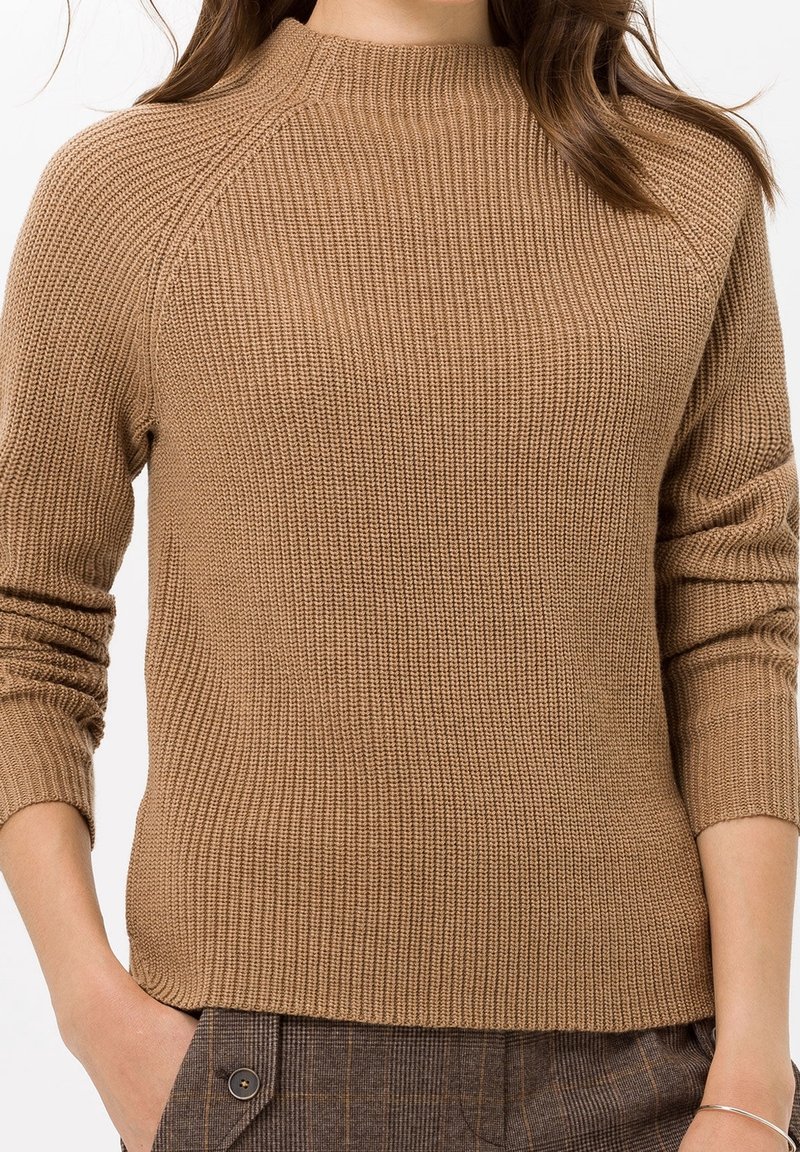 Pull marron côtelé avec un col montant et des manches raglan. Matière tricotée texturée, corps ajusté et ourlet légèrement raccourci.
