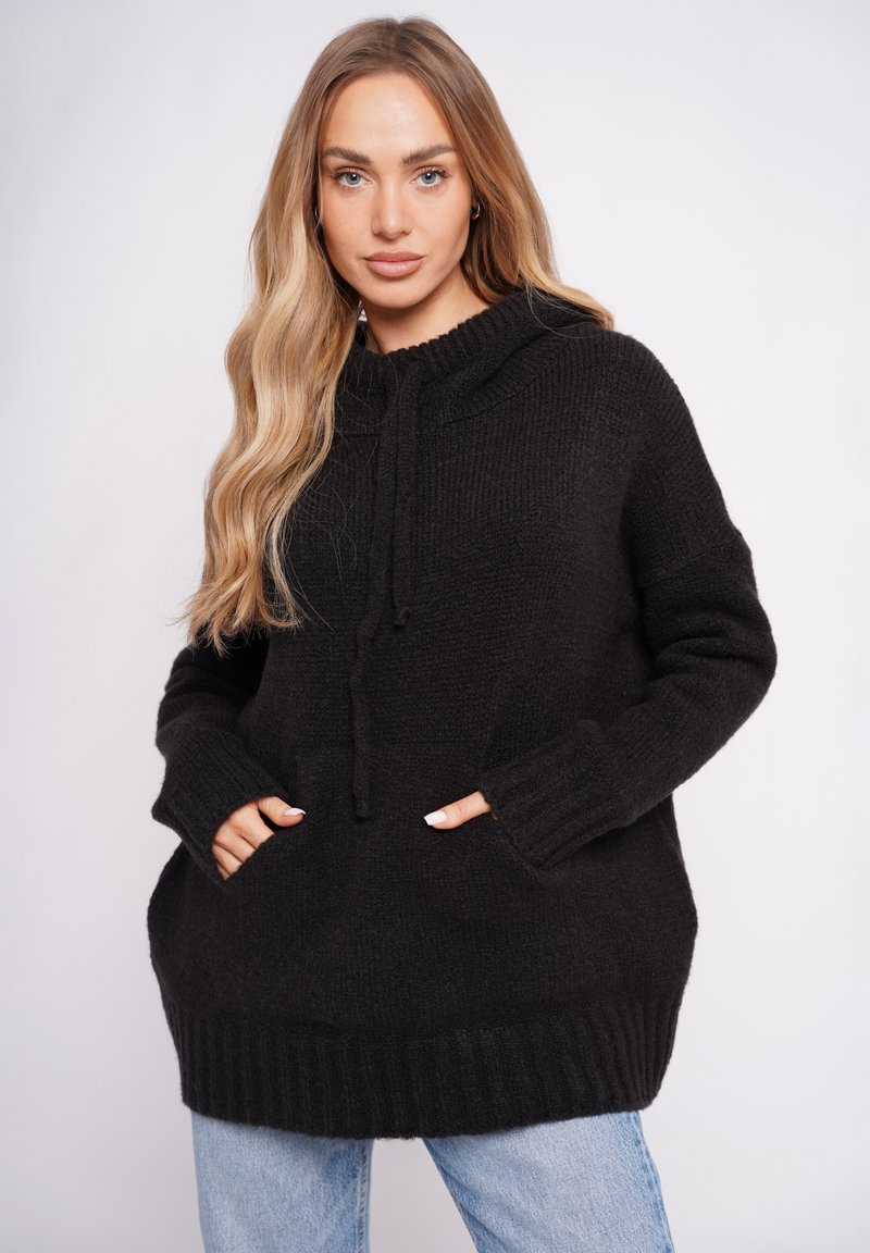 Czarna, dzianinowa, oversize'owa bluza z kapturem, ze sznurkiem, ściągaczem na dole i bocznymi kieszeniami, wykonana z miękkiego materiału, z długimi rękawami.